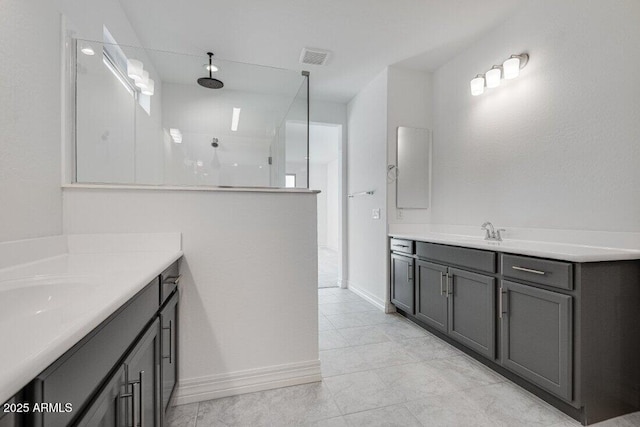 bathroom with two vanities, visible vents, a sink, a walk in shower, and baseboards