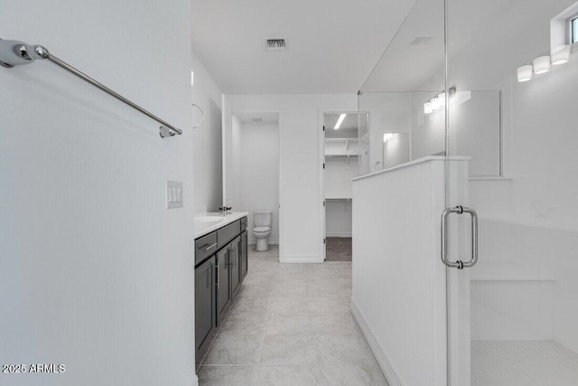 bathroom featuring visible vents, baseboards, toilet, vanity, and a shower stall