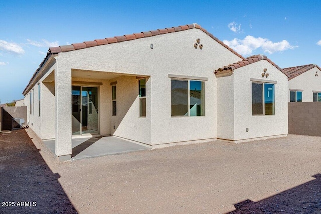 rear view of property with a tiled roof, a patio area, a fenced backyard, and stucco siding