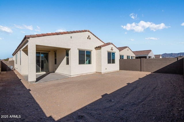 rear view of house with a patio area, a fenced backyard, a tile roof, and stucco siding