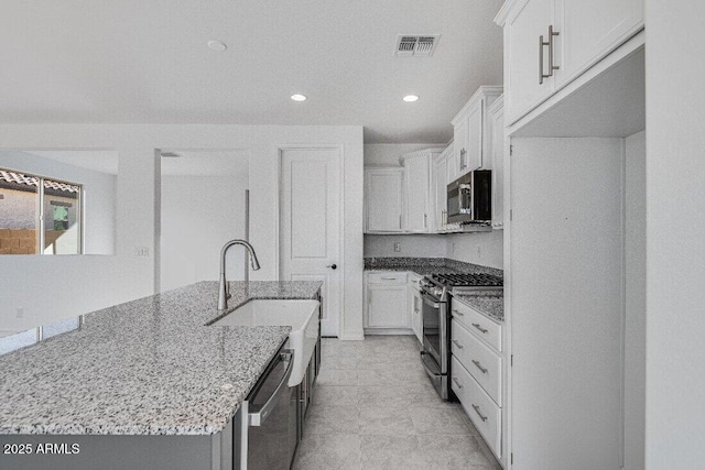 kitchen featuring stainless steel appliances, white cabinets, visible vents, and light stone countertops