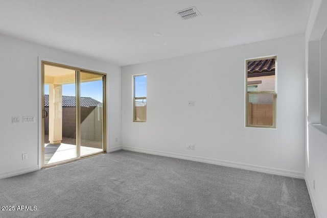 empty room with carpet floors, visible vents, and baseboards