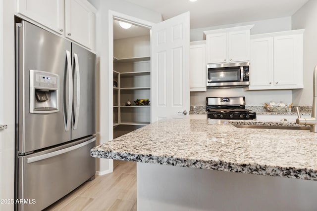 25876 N 162nd Dr, Surprise, AZ 85387 - kitchen with stainless steel appliances, white cabinetry, light stone countertops, and light wood-style floors
