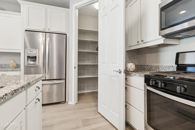 25876 N 162nd Dr, Surprise, AZ 85387 - kitchen with stainless steel appliances, white cabinetry, light stone countertops, and light wood-style floors