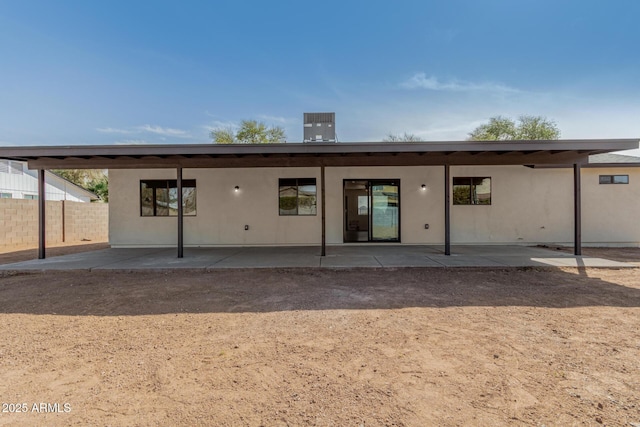 rear view of property featuring a patio area, fence, and stucco siding