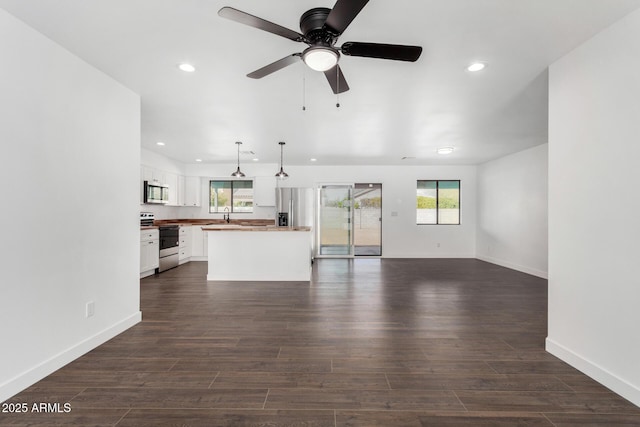 unfurnished living room with dark wood-type flooring, recessed lighting, plenty of natural light, and a sink