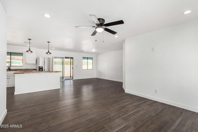 unfurnished living room featuring recessed lighting, dark wood finished floors, baseboards, and ceiling fan