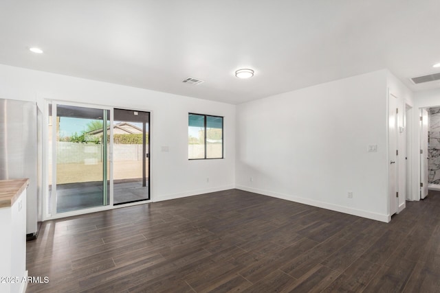 unfurnished room with baseboards, visible vents, dark wood-type flooring, and recessed lighting