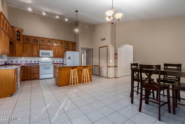 kitchen with sink, an inviting chandelier, pendant lighting, white appliances, and a kitchen island