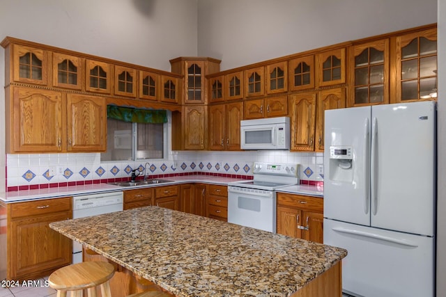 kitchen featuring sink, a center island, tasteful backsplash, white appliances, and a breakfast bar