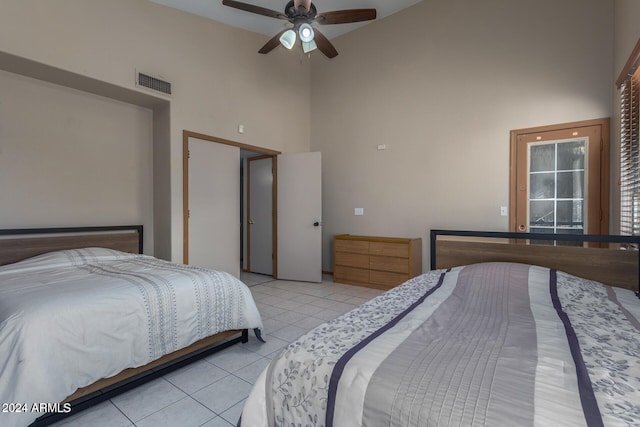 tiled bedroom with ceiling fan and a towering ceiling