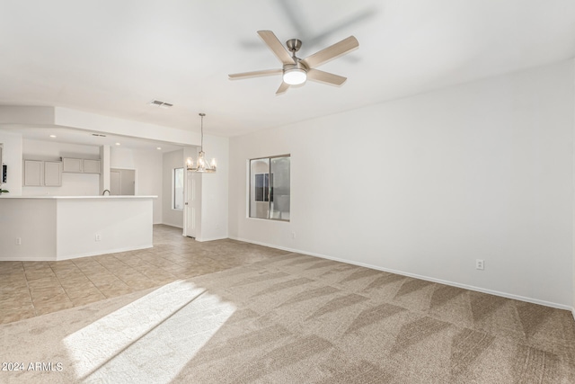 unfurnished living room featuring light carpet and ceiling fan with notable chandelier