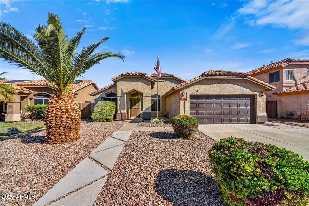 mediterranean / spanish house with concrete driveway, a tiled roof, a garage, and stucco siding