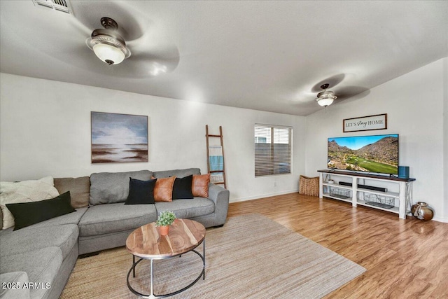 living room featuring baseboards, wood finished floors, visible vents, and ceiling fan