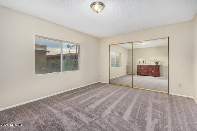 unfurnished bedroom featuring a closet, carpet floors, and a textured ceiling