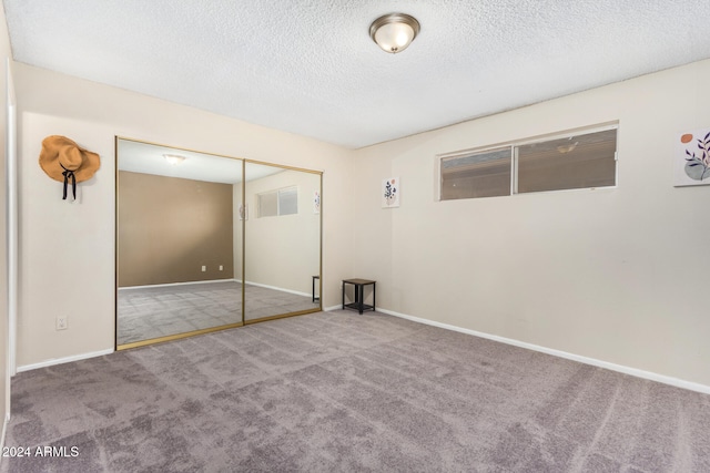 unfurnished bedroom with carpet flooring, a textured ceiling, and a closet