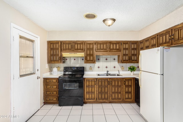 kitchen with sink, black electric range, decorative backsplash, light tile patterned floors, and white fridge