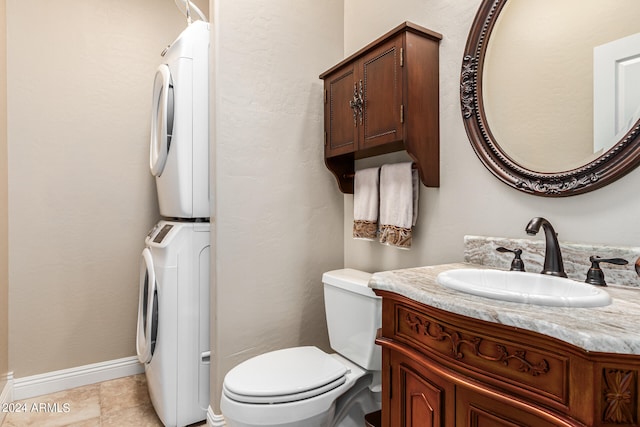 bathroom with tile patterned flooring, vanity, stacked washing maching and dryer, and toilet