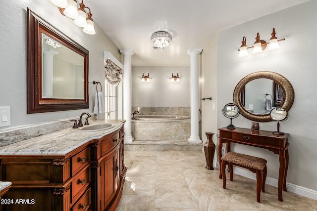 bathroom featuring vanity, ornate columns, tiled tub, and an inviting chandelier