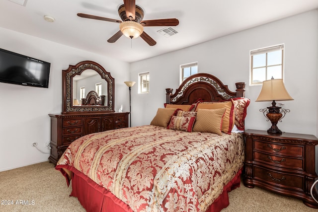 bedroom with ceiling fan, light colored carpet, and multiple windows