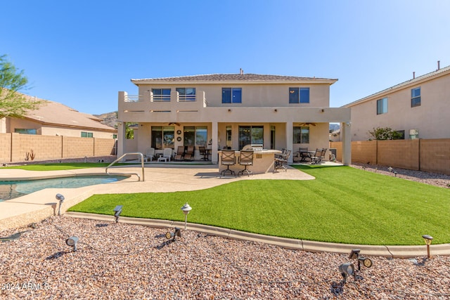 back of property featuring a patio, a fenced in pool, ceiling fan, and exterior kitchen