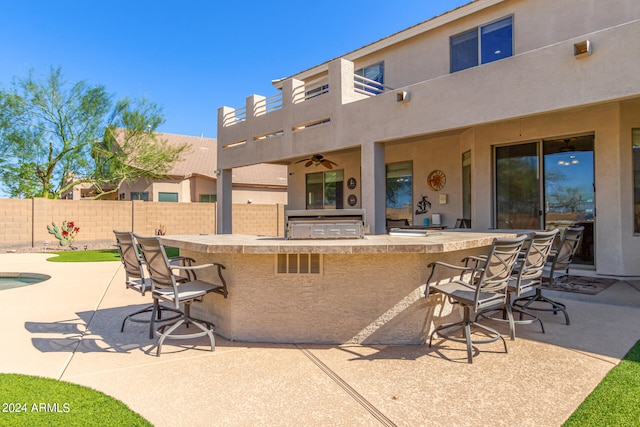 view of patio featuring a bar, an outdoor kitchen, and ceiling fan