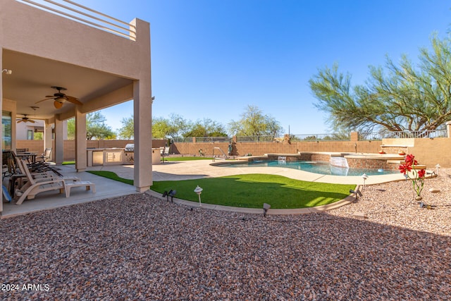 view of yard with pool water feature, ceiling fan, a swimming pool with hot tub, exterior kitchen, and a patio