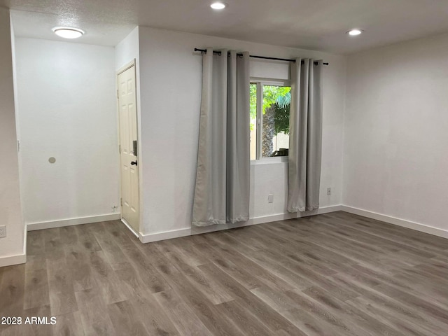 spare room with a textured ceiling and hardwood / wood-style flooring