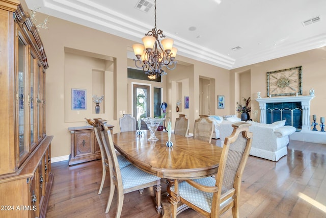 dining room featuring dark wood-type flooring, an inviting chandelier, and a tiled fireplace