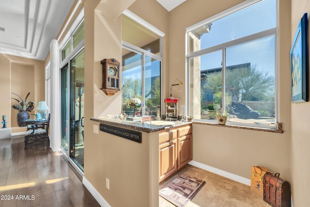 kitchen with light brown cabinetry and dark stone counters