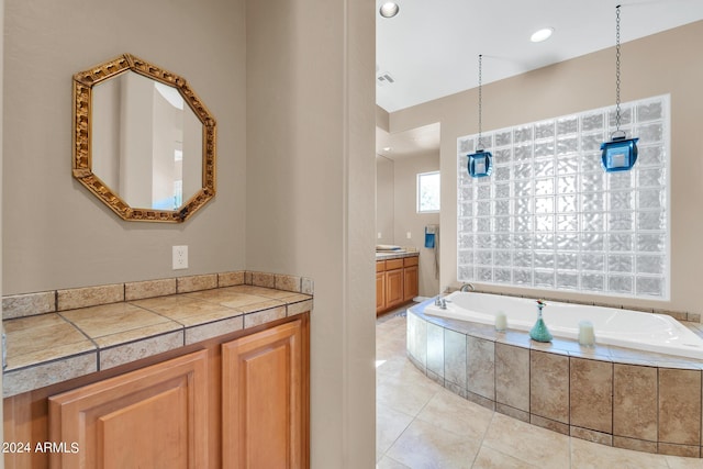 bathroom with tiled bath, tile patterned flooring, and vanity