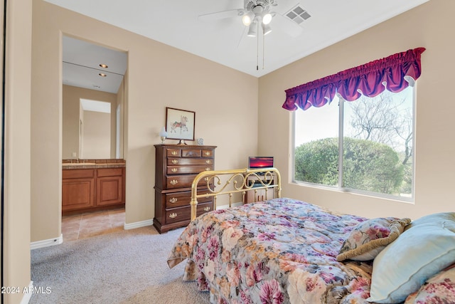 bedroom with ceiling fan, light carpet, sink, and ensuite bathroom