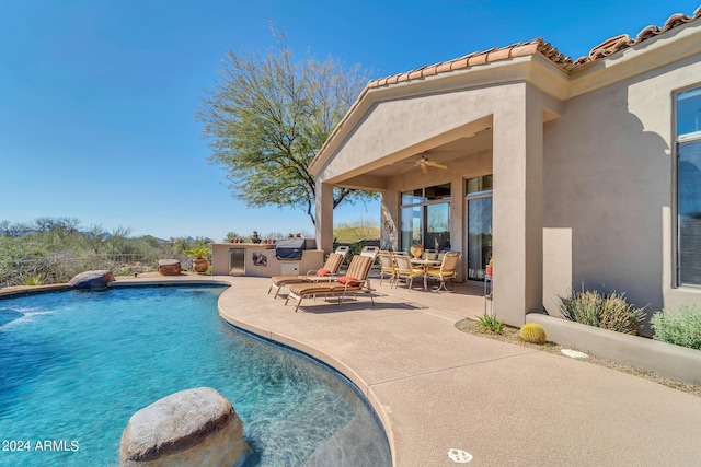 view of pool with exterior kitchen, ceiling fan, and a patio