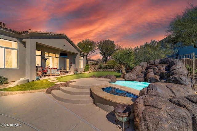 pool at dusk featuring an outdoor fire pit and a patio