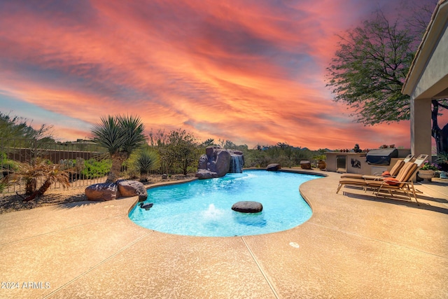 pool at dusk with pool water feature and a patio