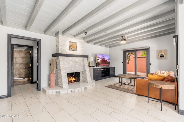 living room featuring beam ceiling, ceiling fan, a stone fireplace, and light tile patterned floors