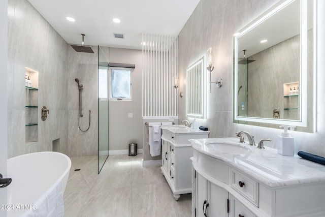 bathroom with plus walk in shower, tile walls, vanity, and tile patterned floors