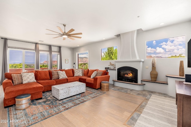 living room featuring a fireplace, light hardwood / wood-style flooring, ceiling fan, and a wealth of natural light