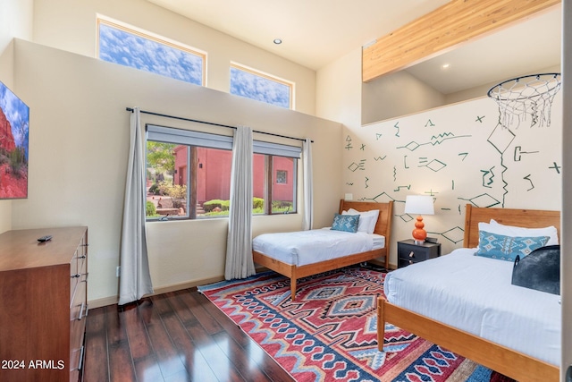 bedroom featuring a high ceiling, beam ceiling, and hardwood / wood-style floors