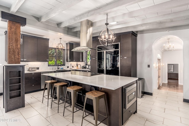 kitchen with a center island, tasteful backsplash, light tile patterned floors, and dark brown cabinetry