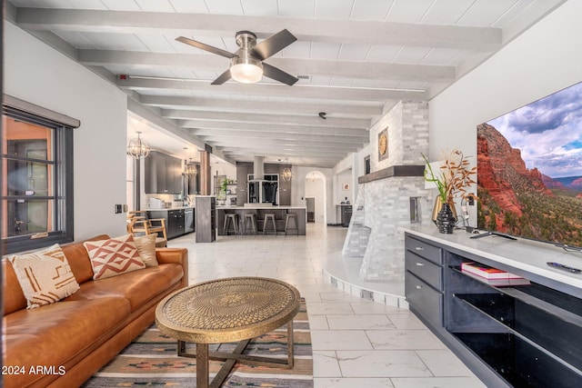 living room featuring ceiling fan with notable chandelier, light tile patterned floors, and beamed ceiling