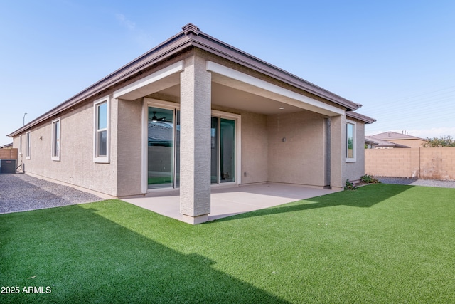 back of property featuring central AC, fence, a yard, stucco siding, and a patio area