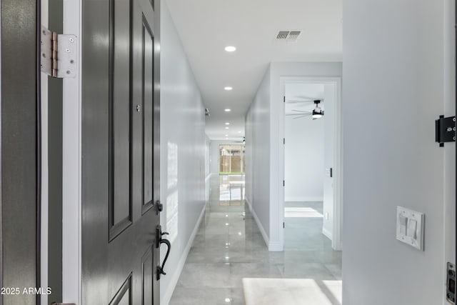 hall featuring baseboards, visible vents, and recessed lighting