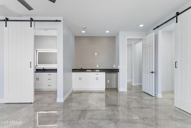 kitchen featuring a barn door, visible vents, dark countertops, white cabinetry, and a sink