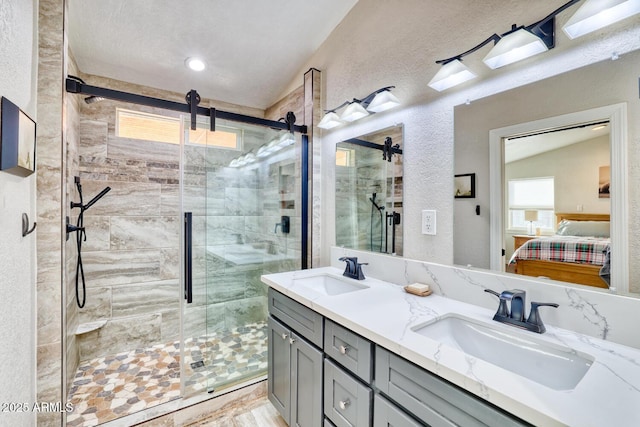 bathroom with a shower with door, vanity, and vaulted ceiling