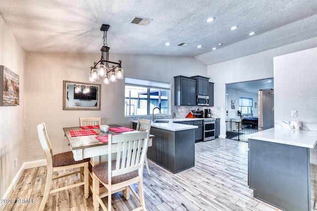 kitchen featuring kitchen peninsula, pendant lighting, stainless steel appliances, and lofted ceiling