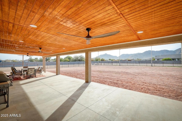 view of patio featuring ceiling fan, a mountain view, and a rural view