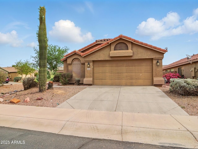 mediterranean / spanish home featuring concrete driveway, stucco siding, a garage, and a tiled roof