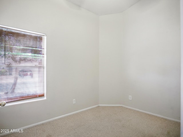 spare room featuring carpet, baseboards, and vaulted ceiling
