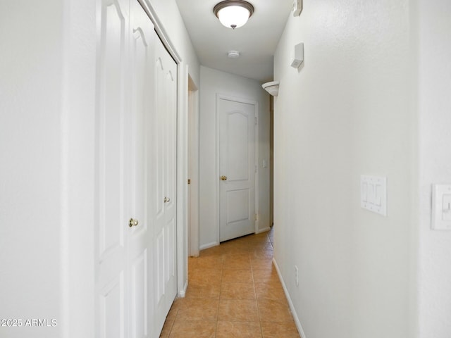 corridor with light tile patterned floors and baseboards